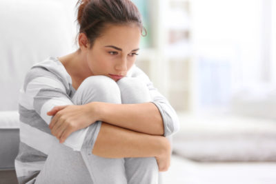 Concerned woman hugging her knees to her chest